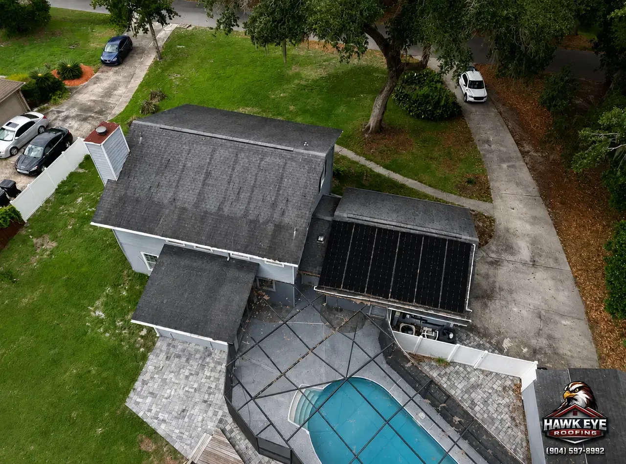 Aerial view of a dark shingle roof with rooftop panels and penetrations on a Jacksonville-area home